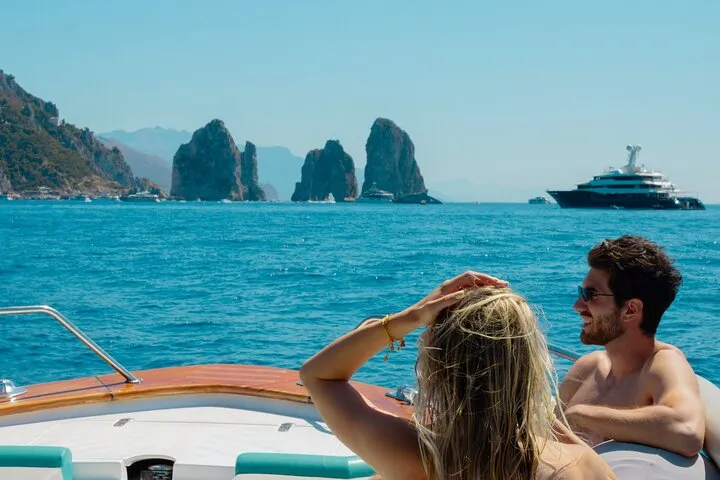 Boat cruising past the Faraglioni rocks with swimmers on a Capri boat tour from Sorrento with swim stops and light lunch, Italy