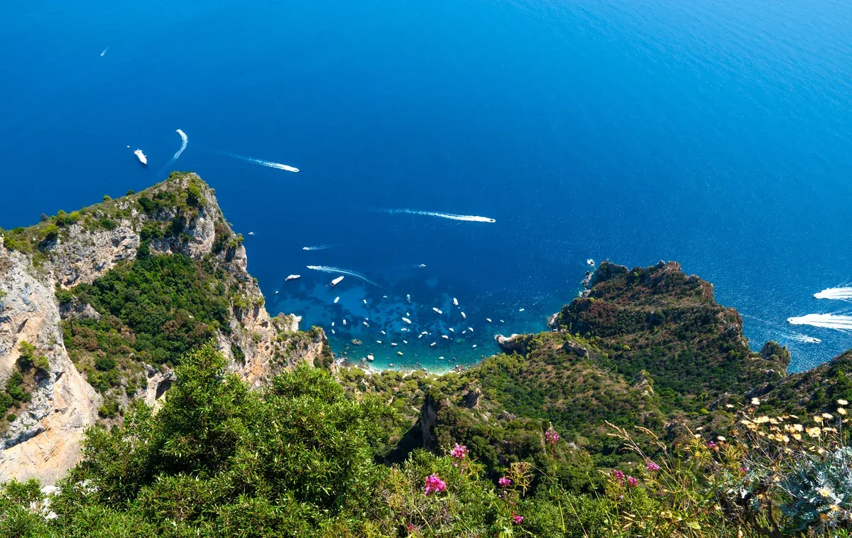 White limestone cliffs of the Capri coastline rising from deep blue water on an island boat trip with grottos, Capri, Italy